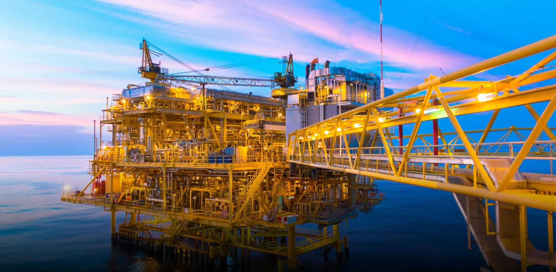 Plataforma offshore iluminada com passarela amarela sobre o mar